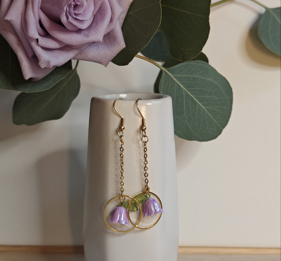 Image of the Lilac Flower Drop Earrings hanging off the side of a small ceramic vase.