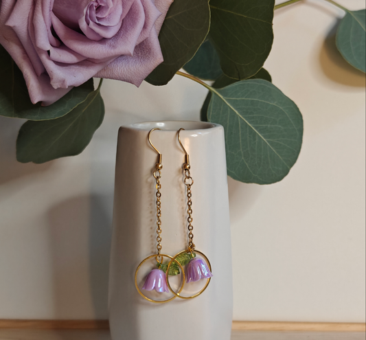 Image of the Lilac Flower Drop Earrings hanging off the side of a small ceramic vase.