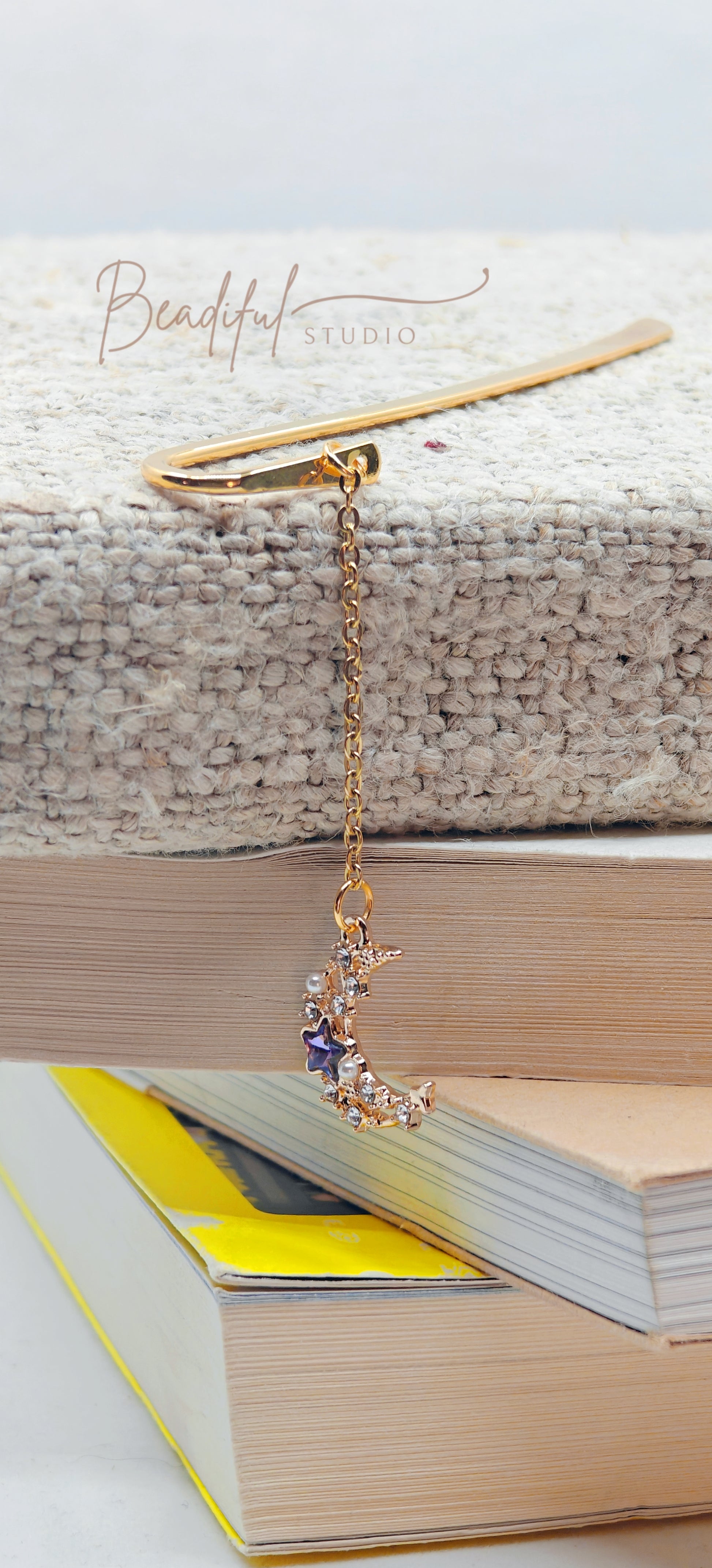 Image of version two Luna bookmark dangling off the side of a pile of stacked books 