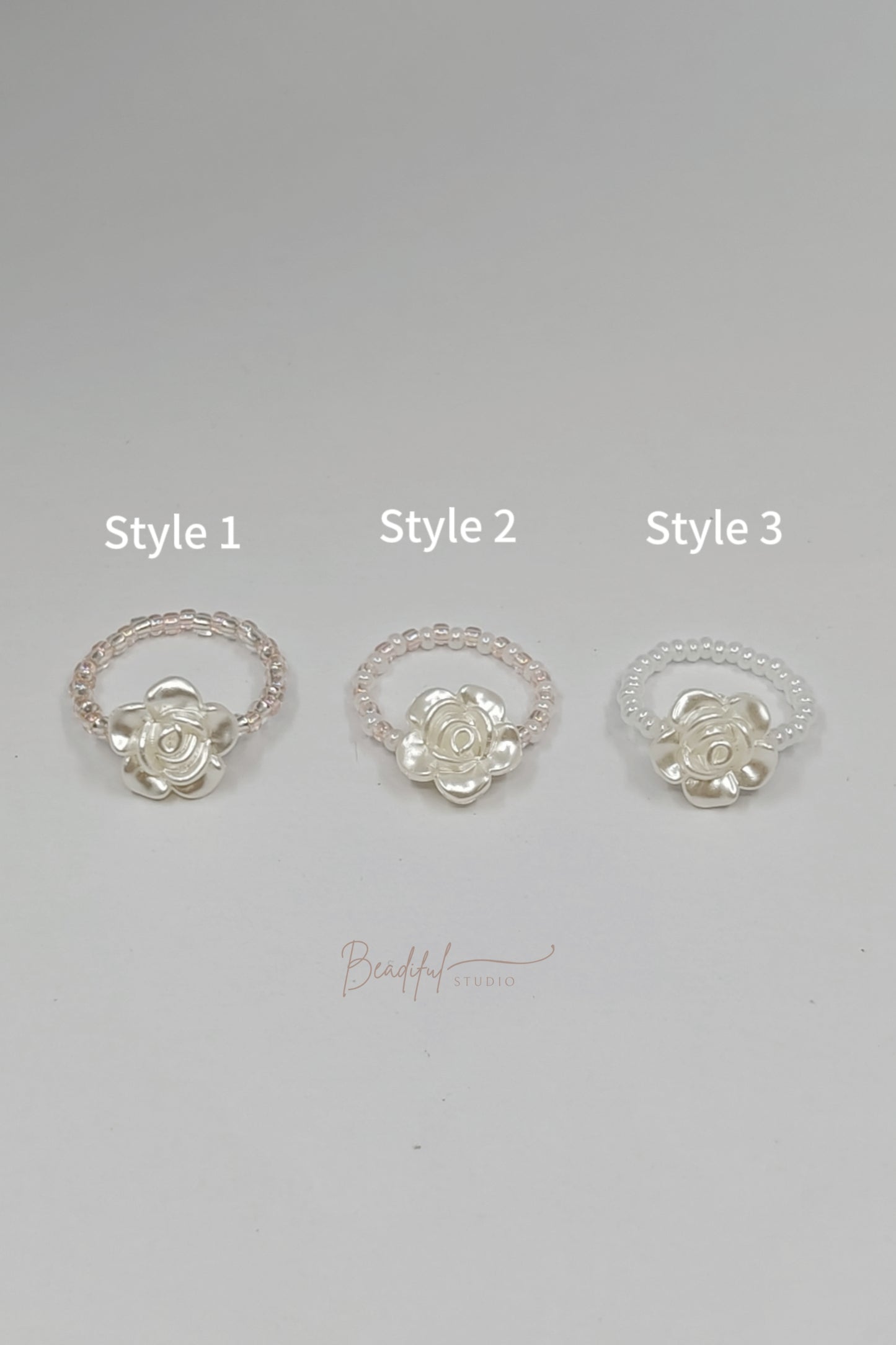 Image of the three color options for the ring. Style 1 - alternating blush pink and clear beads featuring an acrylic white rose. Style 2 - alternating blush pink and white beads featuring an acrylic white rose. Style 3 - All white beads featuring an acrylic white rose.