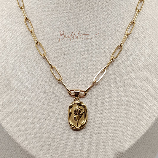 Image of a gold tone necklace that features a stainless steel gold color tulip pendant and gold color paperclip chain