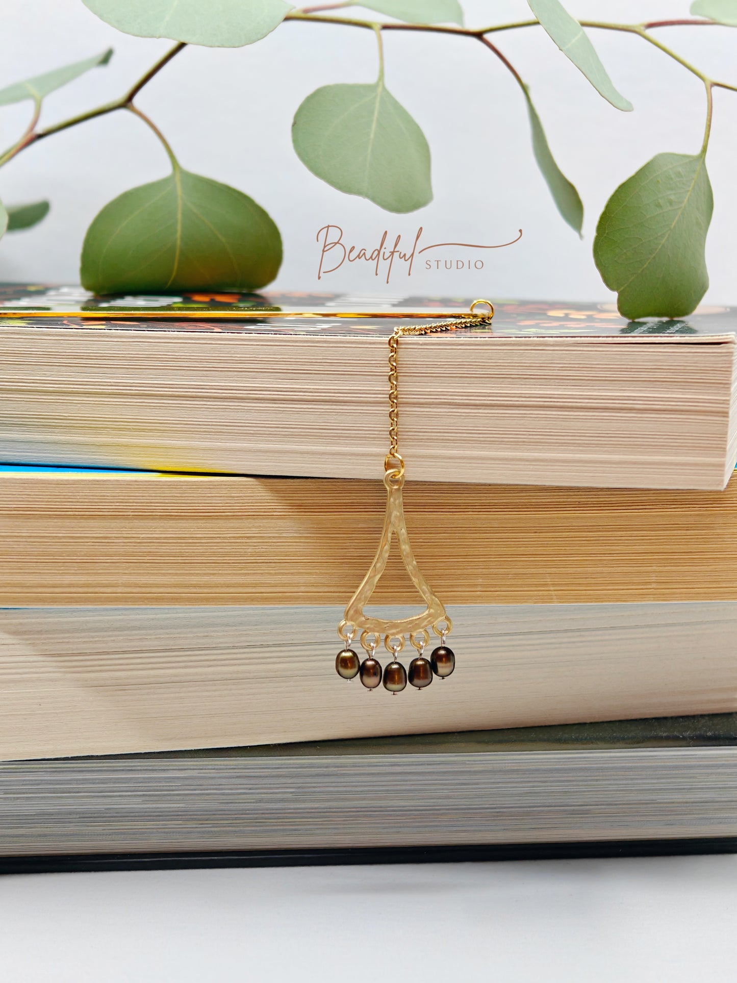 Image of the Celeste bookmark dangling off the side of a pile of stacked books.