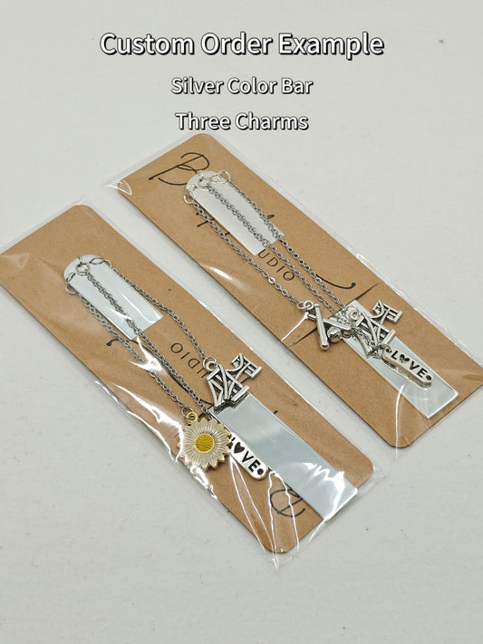 Image of a sample customized order I did for a couple. Two rectangular silver plated metal bookmarks with three charms each.