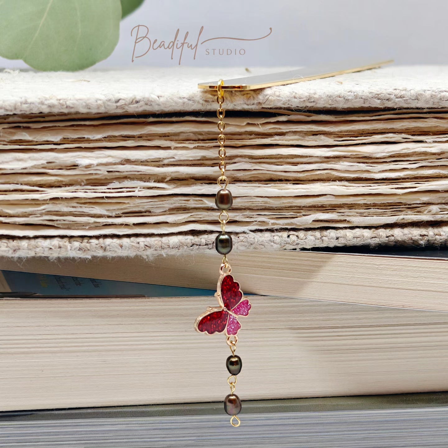 Image of the Aurora bookmark dangling off the side of a pile of stacked books.